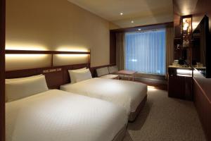 a hotel room with two beds and a window at Candeo Hotels Osaka Shinsaibashi in Osaka