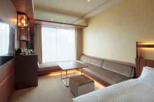 a room with a couch and a table and a window at Candeo Hotels Osaka Shinsaibashi in Osaka