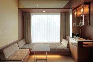 a room with a large window with a bench and a table at Candeo Hotels Osaka Shinsaibashi in Osaka