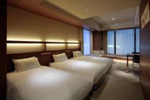 a hotel room with two beds and a desk at Candeo Hotels Osaka Shinsaibashi in Osaka