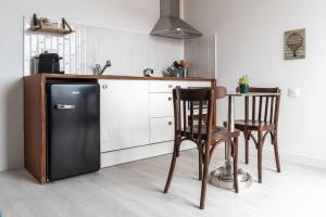a kitchen with a black refrigerator and two chairs at La Javanaise in Narbonne-Plage
