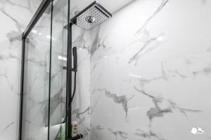 a shower in a bathroom with white marble walls at MBA Splendide Appart - Wilson 1 - Mairie de Montreuil in Montreuil