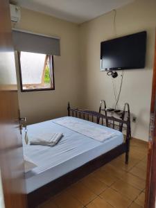 - une chambre avec un lit et une télévision murale dans l'établissement Poutur Pousada, à Maceió