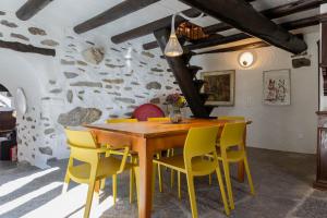 Verzasca Lodge Ofelia في Sonogno: غرفة طعام مع طاولة خشبية وكراسي صفراء