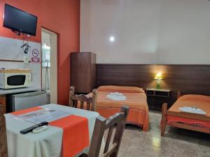 Zimmer mit 2 Betten, einem Tisch und einer Mikrowelle in der Unterkunft Costas del Paraiso in Colón