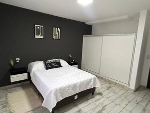 een slaapkamer met een wit bed en een zwarte muur bij Luxury Apartment Posadas 2 in Posadas