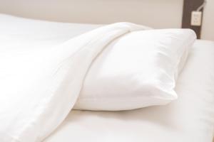 a white pillow on top of a bed at GuestHouse OneWorld Shijo四条京町屋 in Kyoto