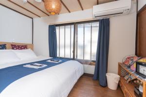 a bedroom with a bed and a large window at GuestHouse OneWorld Shijo四条京町屋 in Kyoto