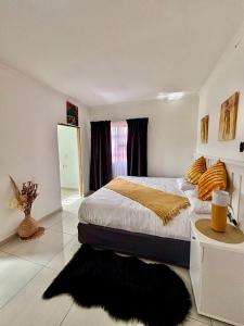 1 dormitorio con 1 cama con alfombra negra en TT’s self-catering apartments, en Qumbu