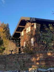 an old log house on a hill behind a stone wall at Chalet atypique Colorado Crans-Montana in Crans-Montana