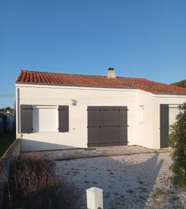 Casa blanca con techo rojo y 2 puertas de garaje en Vacances familiales sur l'Île de Noirmoutier, en Barbâtre