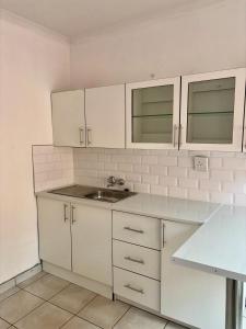 una cocina con armarios blancos y fregadero en TT’s self-catering apartments, en Qumbu