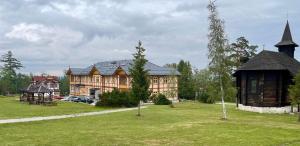 a large building with a grass field in front of it at Vila Kollár in Vysoké Tatry