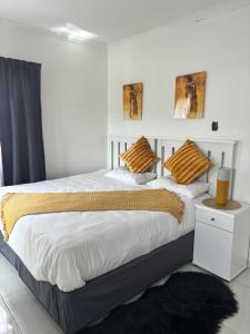 1 dormitorio blanco con 1 cama grande con almohadas de color naranja en TT’s self-catering apartments, en Qumbu