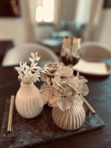dois vasos brancos com flores sobre uma mesa em Stilvolle Wohnung in Bestlage em Bayreuth