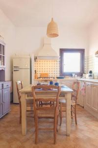a kitchen with a wooden table and chairs in a kitchen at Vicolo della Luna in Castelsardo