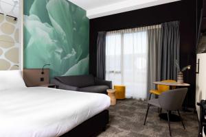 een hotelkamer met een bed en een stoel bij Otium Hotel Roosendaal in Roosendaal