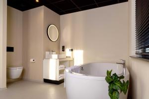 a bathroom with a large tub and a toilet at Otium Hotel Roosendaal in Roosendaal