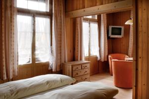 a bedroom with a bed and a desk and a television at Hotel Saanerhof in Gstaad