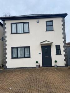 a white house with black windows and a driveway at Detached Boutique Luxury 3 Bed Villa Free Parking & WI-FI in Kingswood