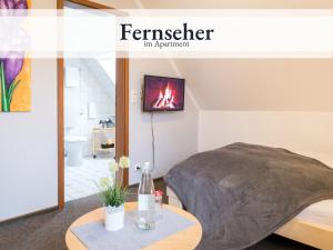Habitación con cama y TV en la pared. en Blumenvilla 9 mit Sauna und Garten, en Schneverdingen
