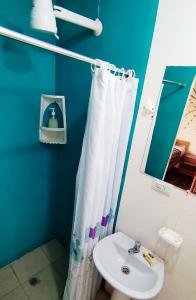 baño con cortina de ducha blanca y lavamanos en Buganvilla Guest House en Ballenita