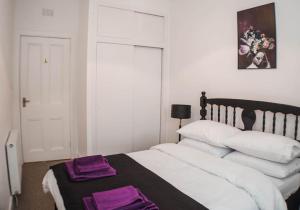 a bedroom with a large bed with purple towels on it at The Scot in Perth