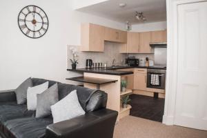 a living room with a black couch and a kitchen at The Scot in Perth