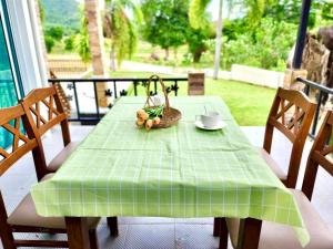 uma mesa verde com uma cesta de frutas e uma chávena em บ้านกลางหุบเขา แก่งกระจาน em Kaeng Krachan