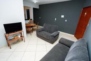 a living room with a couch and a chair and a tv at Aconchego Veredas II in Viçosa