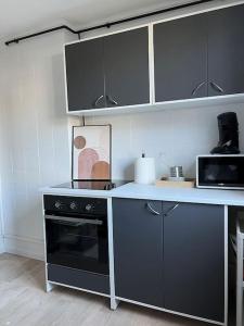 a kitchen with a black stove and a microwave at Le Phoenix, proche stations ski et Campus Univers. in Gières
