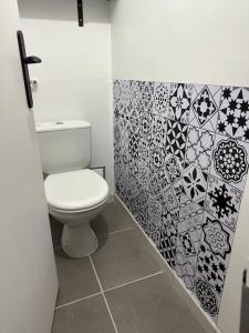 a bathroom with a toilet and a tile wall at Le Phoenix, proche stations ski et Campus Univers. in Gières