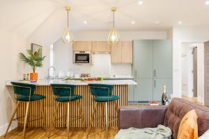 a kitchen with a bar with green bar stools at Sea Breeze - Pebbles in Bournemouth