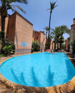 a large blue swimming pool with palm trees at Riad with 3 Swimming Pools in Marrakech