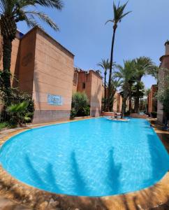 a large blue swimming pool with palm trees at Riad with 3 Swimming Pools in Marrakesh