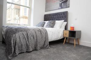 een slaapkamer met een bed met een grijze deken en een raam bij OYO Hotel Rafay in Blackburn