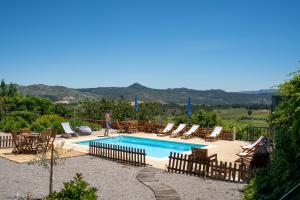 a man standing next to a swimming pool with chairs and tables at Quinta do Sol in Alijó