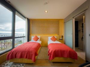 two beds in a room with a large window at Mihman Hotel in Tuzla