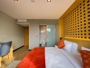 a bedroom with a large white bed with orange pillows at Mihman Hotel in Tuzla