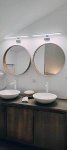 a bathroom with two sinks and two mirrors at Coco Marco Hôtel in Nyons