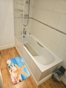 a bathroom with a bath tub with a starfish rug at HEATHROW MANSION SHUTTLES in Uxbridge