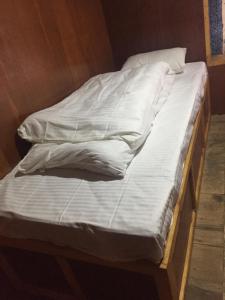 an unmade bed with white sheets on top of it at Tribeni Lodge Restaurant And Bar in Phakding