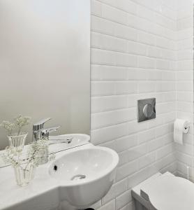 biała łazienka z umywalką i toaletą w obiekcie Bez Kantów Art Rooms w Warszawie