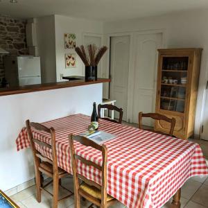 een keuken met een rood en wit geruite tafel en stoelen bij La petite corbière - Chez Hélène - Gîtes en baie in Jullouville-les-Pins