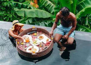 un par de personas de pie alrededor de una mesa en el agua en Rabot Hotel From Hotel Chocolat, en Soufrière