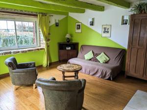 ein Wohnzimmer mit grünen Wänden, einem Sofa und Stühlen in der Unterkunft La petite corbière - Chez Hélène - Gîtes en baie in Jullouville-les-Pins
