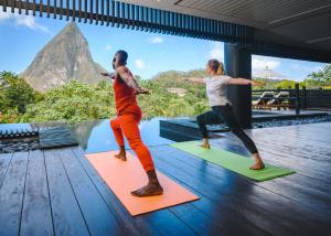 Due persone che fanno yoga sui materassini di fronte alla piscina di Rabot Hotel From Hotel Chocolat a Soufriere