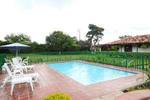 a swimming pool with two chairs and an umbrella at Finca Hotel Betulia in La Tebaida