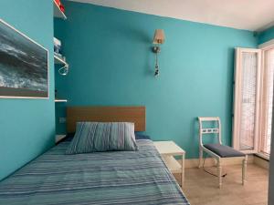 - une chambre avec des murs bleus, un lit et une chaise dans l'établissement The Lodge by the sea, à Ischia