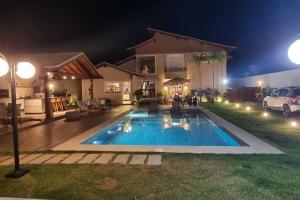 a swimming pool in front of a house at night at Recanto dos Canários - Búzios in Búzios